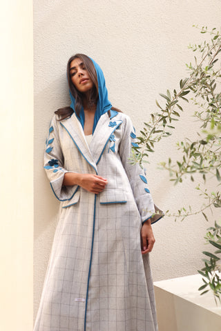 Shimmer-The Art of Layers S.LO1 - a luxurious grey check abaya adorned with intricately cut leather floral motifs, beautifully layered across the design and finished with refined blue piping.