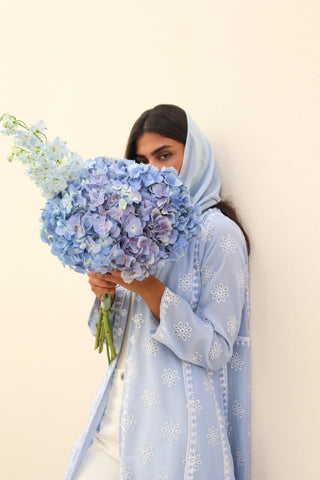 The Language Of Flowers S.FO1-an elegant powder blue abaya featuring delicate floral cutwork fabric and intricate white embroidery.