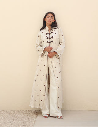 Letters From Kyoto S.KO5 is a refined ivory printed abaya featuring delicate brown piping and elegant knot buttons. 