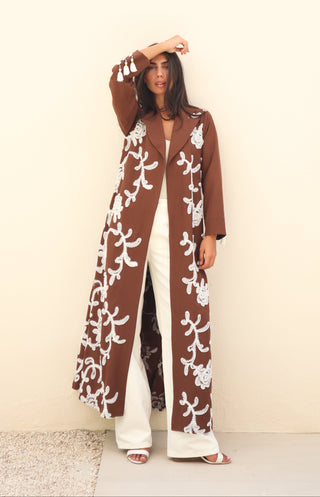 Shimmer-The Art of Layers S.LO4 - a luxurious brown abaya adorned with delicate white floral patches and elegant tassel details.
