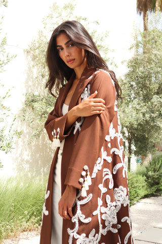 Shimmer-The Art of Layers S.LO4 - a luxurious brown abaya adorned with delicate white floral patches and elegant tassel details.