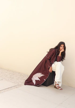 The Language Of Flowers S.FO5 -striking burgundy abaya adorned with delicate white floral details and elegant contrast piping.
