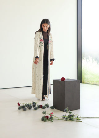An elegant ivory abaya adorned with delicate floral embroidery and defined by refined black trim.
