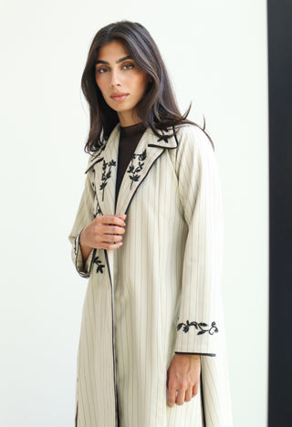 The Art of Layers S.LO11 - luxurious ivory striped abaya adorned with intricate black floral embroidery and refined piping details. 