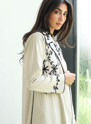 The Art of Layers S.LO11 - luxurious ivory striped abaya adorned with intricate black floral embroidery and refined piping details. 