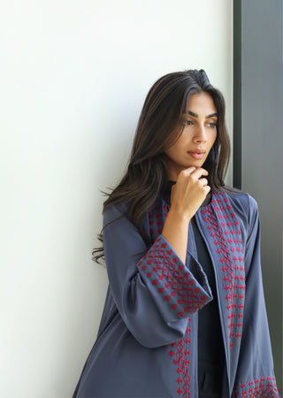 The Language Of Flowers S.FO7 is a sophisticated grey abaya enhanced with striking red geometric embroidery for a distinctive, contemporary finish.